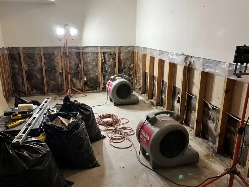 Red air movers drying a room with the lower drywall cut away