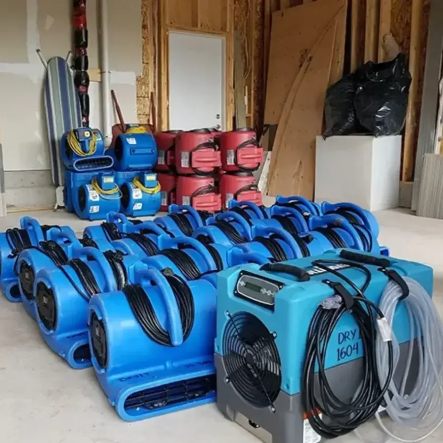 Air movers and dehumidifiers lined up in an opened room for structural drying