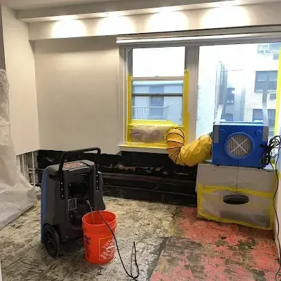 Air movers and a dehumidifier drying a room with its flooring removed