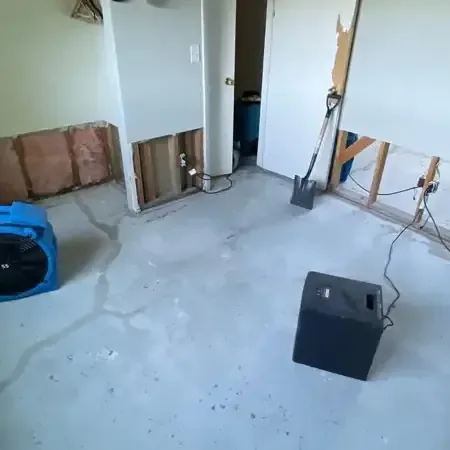 Air movers and a dehumidifier drying a room with flooring removed