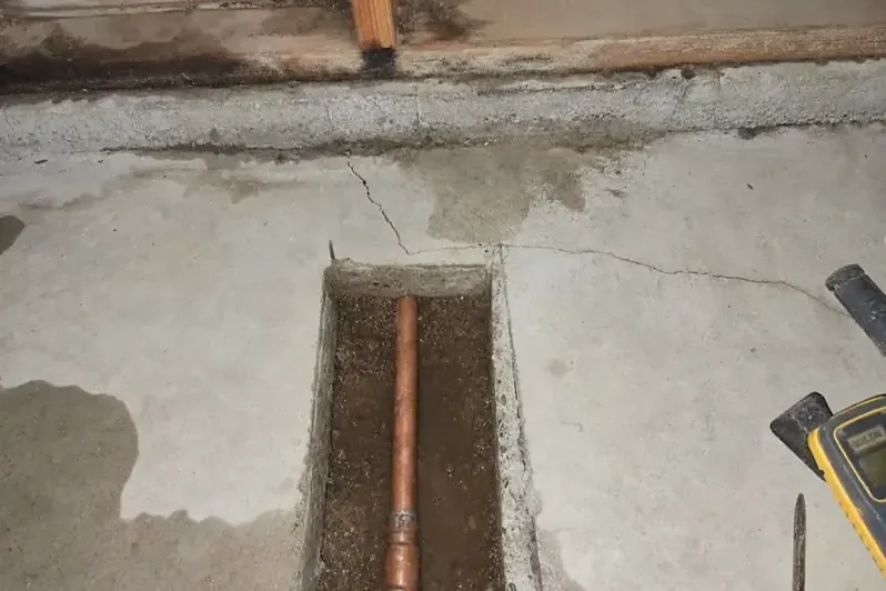 Concrete slab trenched open to expose a leaking copper water line
